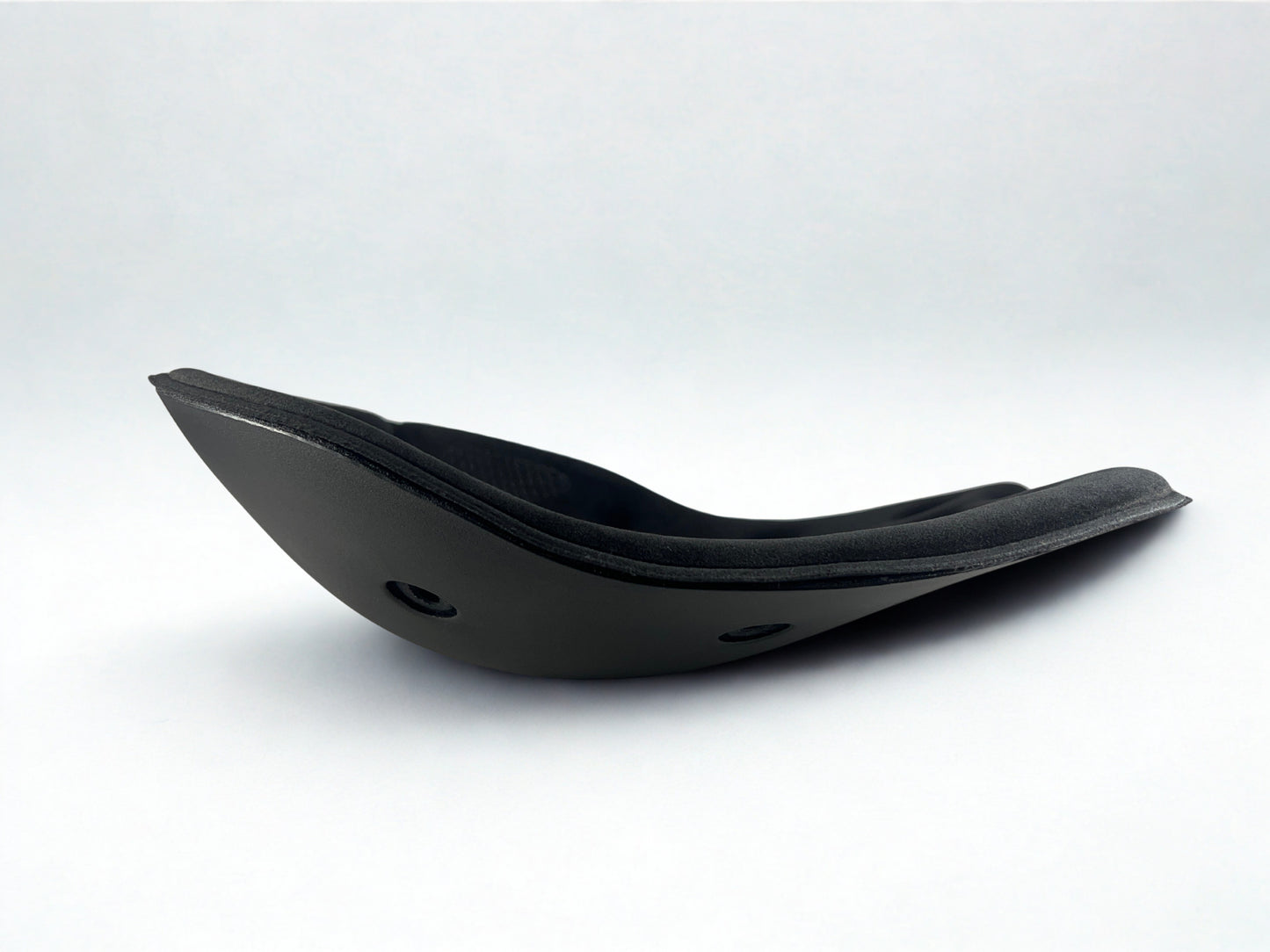 Side profile of a black BackJoy posture corrector seat, showing its active stabilizing curved design.