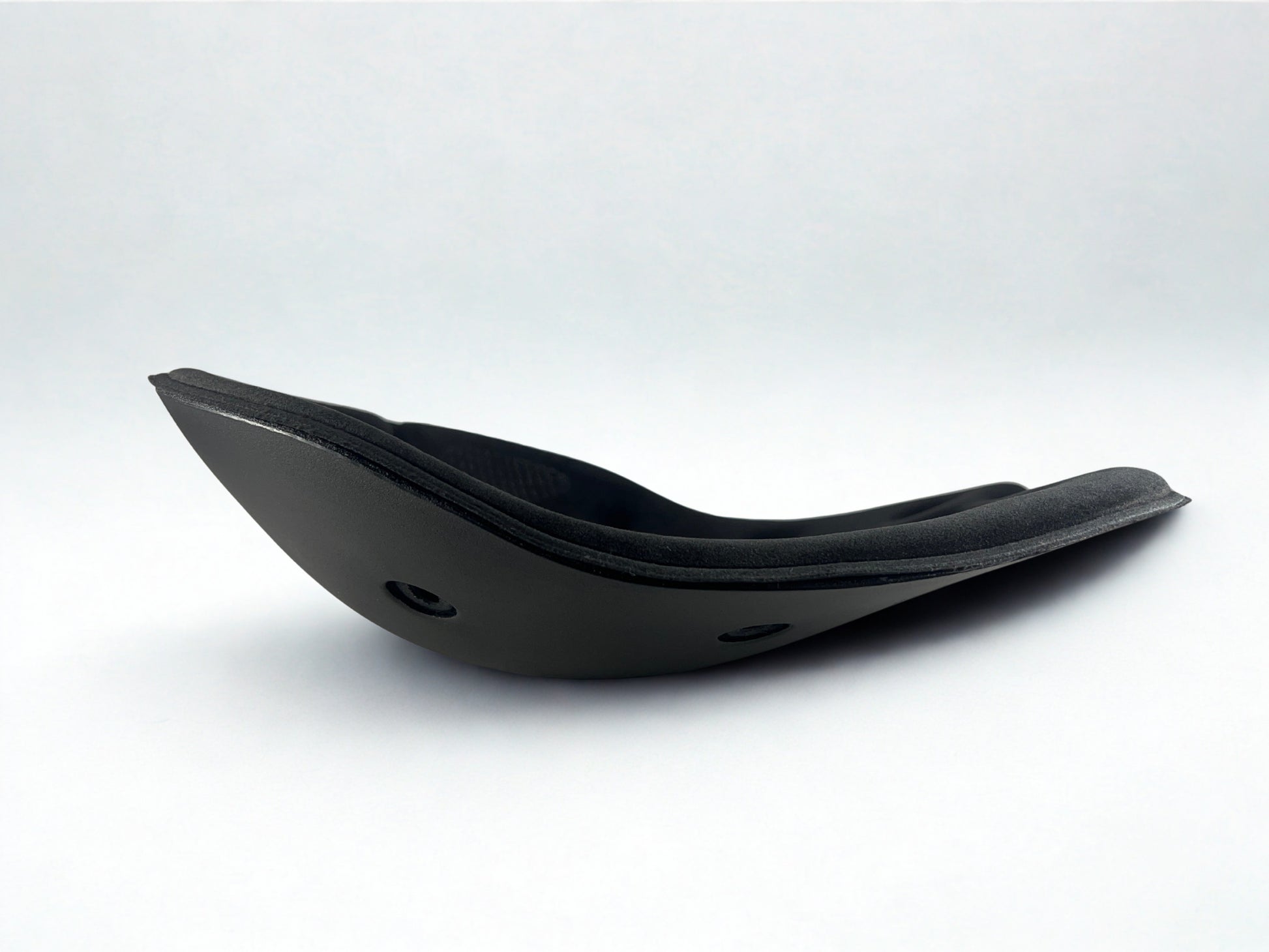 Side profile of a black BackJoy posture corrector seat, showing its active stabilizing curved design.